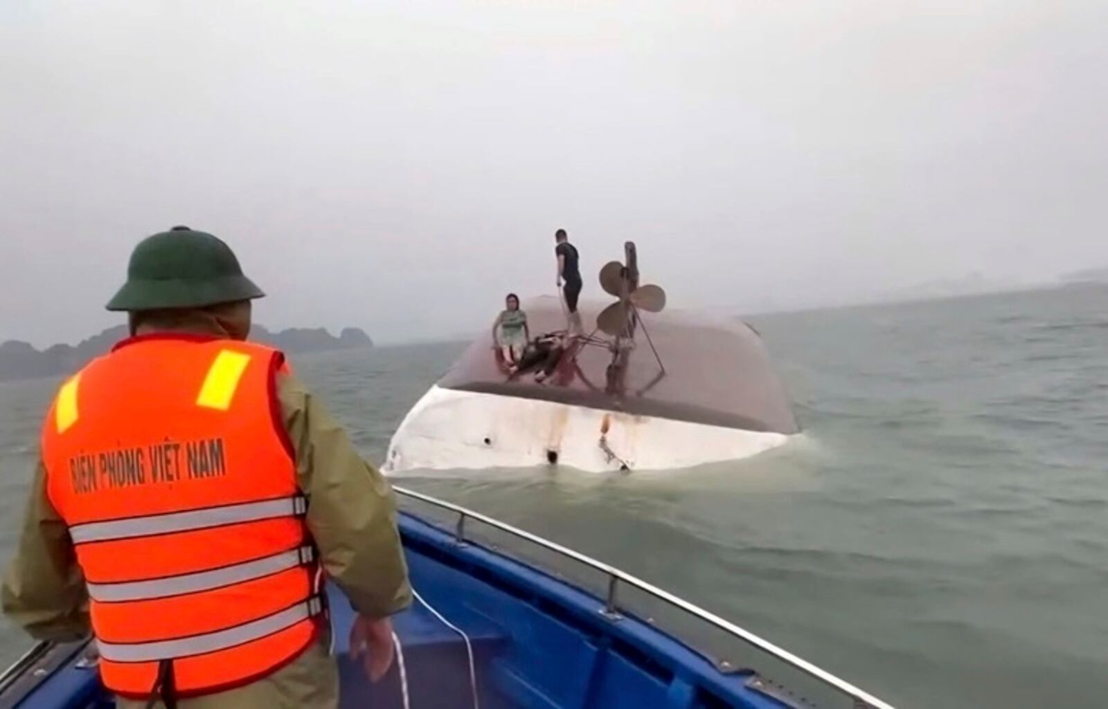 This image from a video provided by QDND shows people on a capsized tourist boat being rescued in Ha Long Bay, Vietnam on Saturday, July 19, 2025. (QDND via AP)
