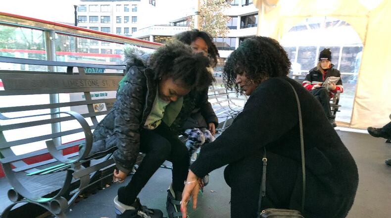 Candace Simmons helps her twins Kay'On and Kay'Lyn with their skates on Saturday at the Speedway Ice Skating Rink. Simmons said she didn't want a shooting incident that occurred Friday evening to interfere with the girls' excitement to skate.