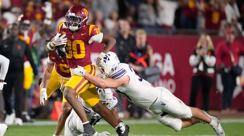 Southern California running back King Miller, left, breaks a tackle by Northwestern linebacker Mac Uihlein during the first half of an NCAA college football game Friday, Nov. 7, 2025, in Los Angeles. (AP Photo/Mark J. Terrill)
