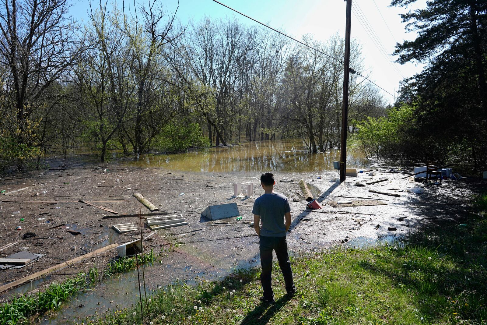 Azariah Boone, of Owenton, Ky, looks out over debris and rising floodwater from the Kentucky River washing up Crittenden Street, Monday, April 7, 2025, in Gratz, Ky. (AP Photo/Carolyn Kaster)