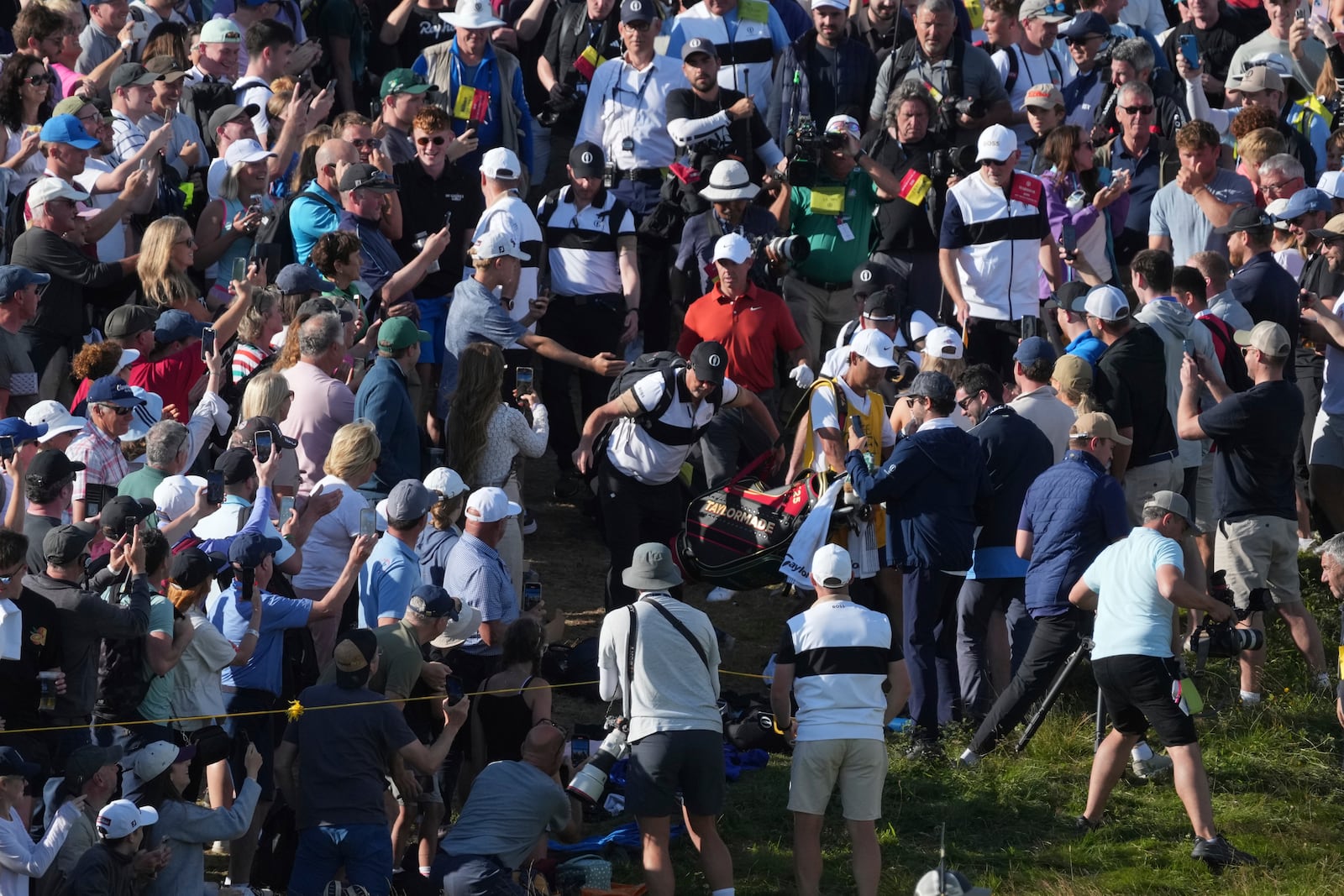 Rory McIlroy of Northern Ireland goes to his ball on the 17th which landed win the crowd during the third round of the British Open golf championship at the Royal Portrush Golf Club, Northern Ireland, Saturday, July 19, 2025. (AP Photo/Jon Super)