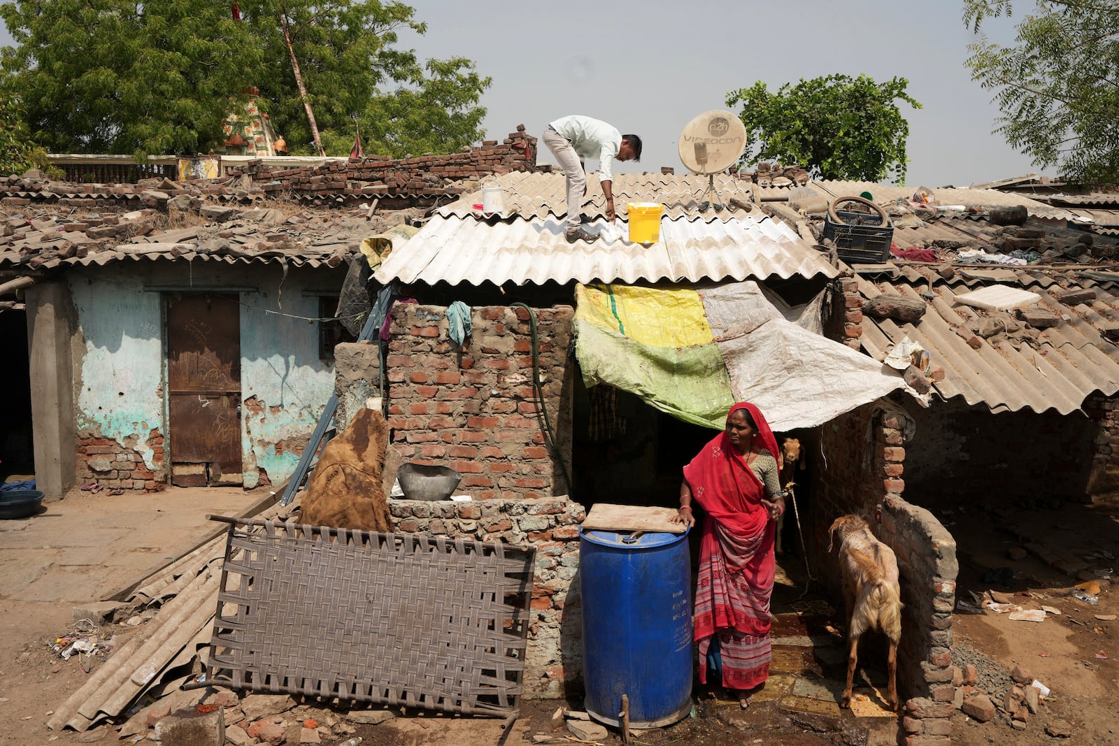 A man applies reflective paint on the roof of a house to reduce indoor heat in Ahmedabad, India, Wednesday, April 2, 2025. (AP Photo/Ajit Solanki)