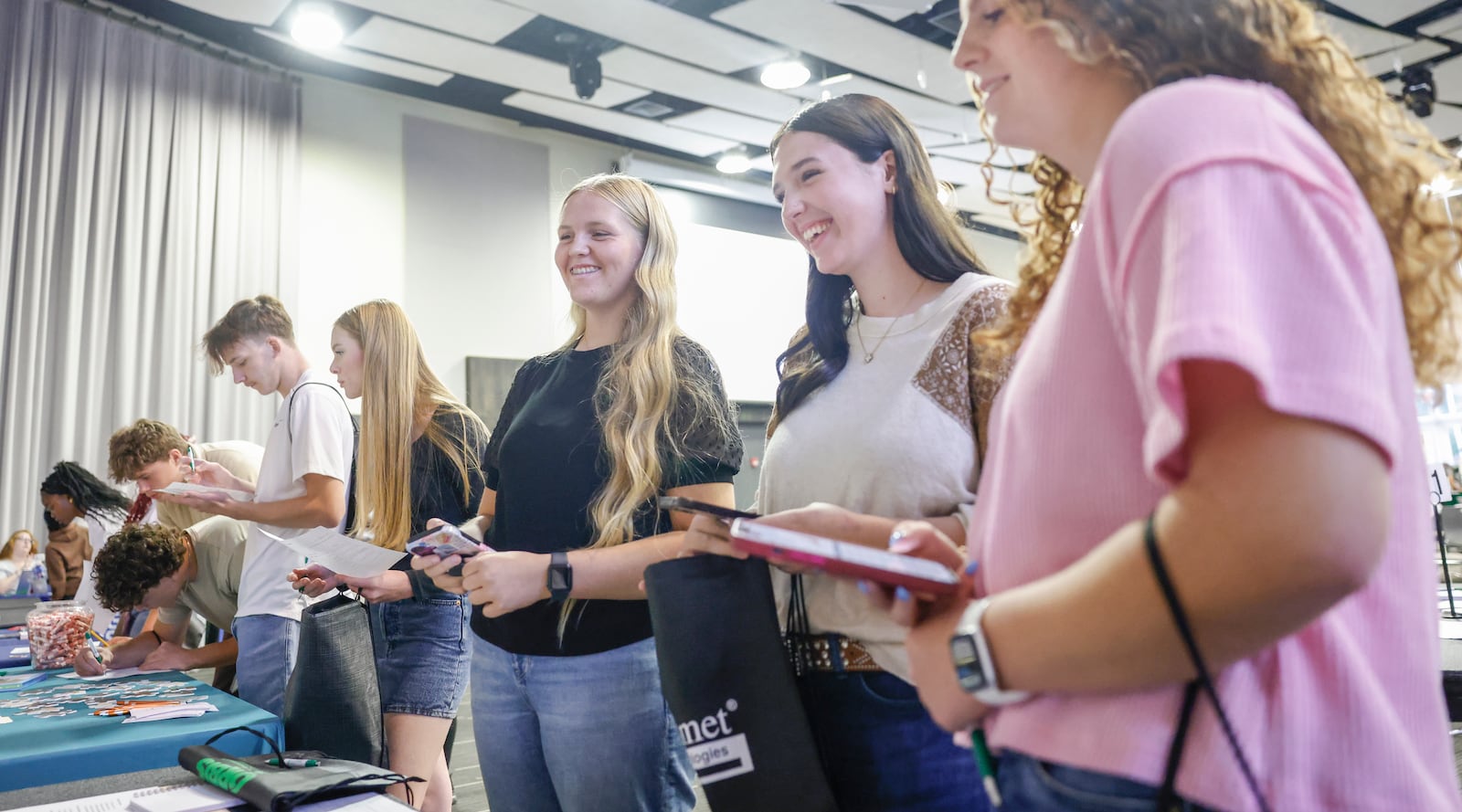 Greenon High School juniors Alydia Lenox, left, Lilly Kelley, center, and Madison Blair laugh while talking to an Edward Jones recruiter during Discovery Day on Tuesday, September 30, 2025, at the Hollenbeck Bayley Center. JOSEPH COOKE/STAFF