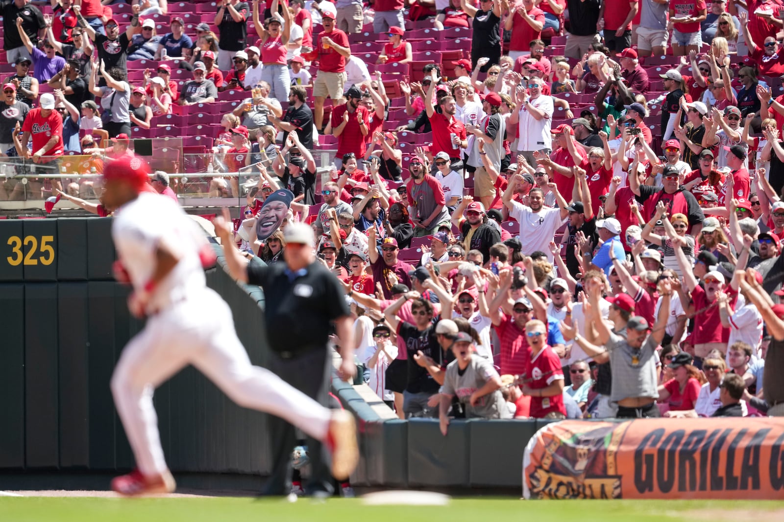 Fans, background, react as Cincinnati Reds' Will Benson, left, rounds the bases after hitting a solo home run during the sixth inning of a baseball game against the Cleveland Guardians, Sunday, May 18, 2025, in Cincinnati. (AP Photo/Jeff Dean)
