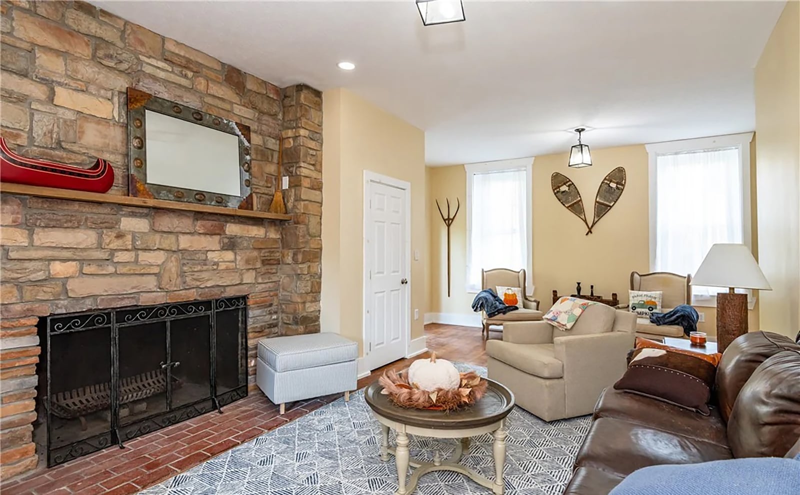 The living room has original hardwood floors, a woodburning fireplace with brick hearth and stacked stone and high ceilings with light fixtures. CONTRIBUTED