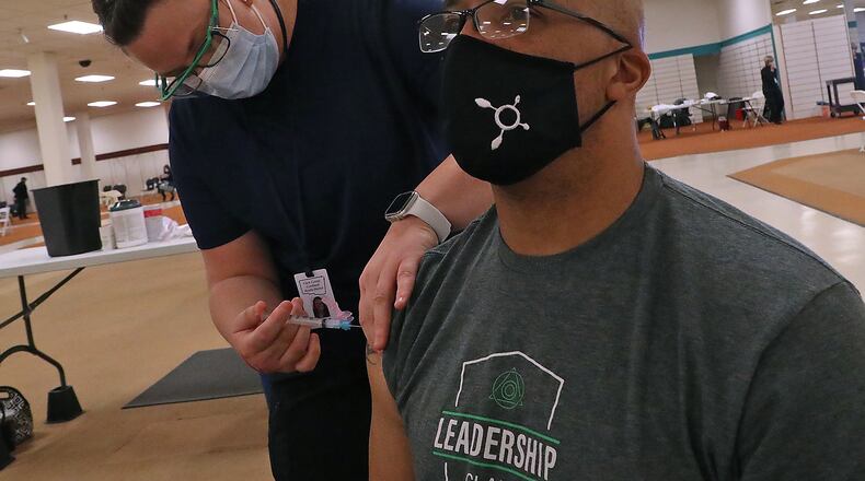 Chris Wallace, a mentor supervisor with Springfield City Schools, gets a COVID-19 vaccine injection. Coronavirus cases at schools in Clark and Champaign counties are under 10. BILL LACKEY/STAFF