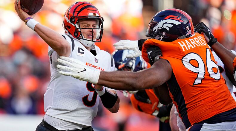 Cincinnati Bengals quarterback Joe Burrow (9) throws under pressure from Denver Broncos defensive end Shelby Harris (96) during the first half of an NFL football game, Sunday, Dec. 19, 2021, in Denver. (AP Photo/Jack Dempsey)