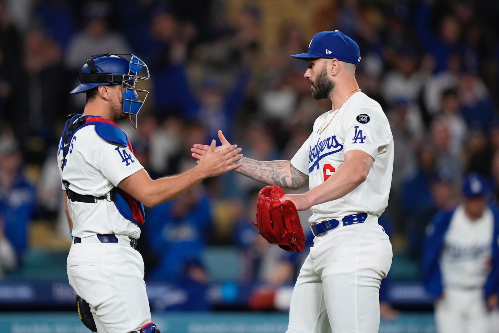 Los Angeles Dodgers catcher Austin Barnes, left, and relief pitcher Tanner Scott congratulate each other after the Los Angeles Dodgers defeated the Colorado Rockies 8-7 in a baseball game Wednesday, April 16, 2025, in Los Angeles. (AP Photo/Mark J. Terrill)