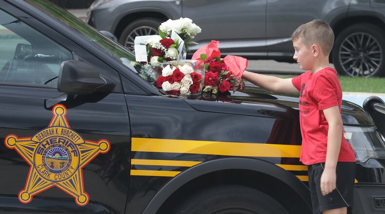 A boy puts flowers on the hood of a Clark County Sheriff's vehicle set up on the Springfield City Hall Plaza as a memorial for Deputy Matthew Yates Monday. BILL LACKEY/STAFF