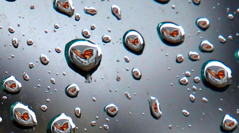 The "Transformation" butterfly mural on the back of the State Theater is reflected in the tiny drops of water on a car window Wednesday, Jan. 24, 2024. BILL LACKEY/STAFF