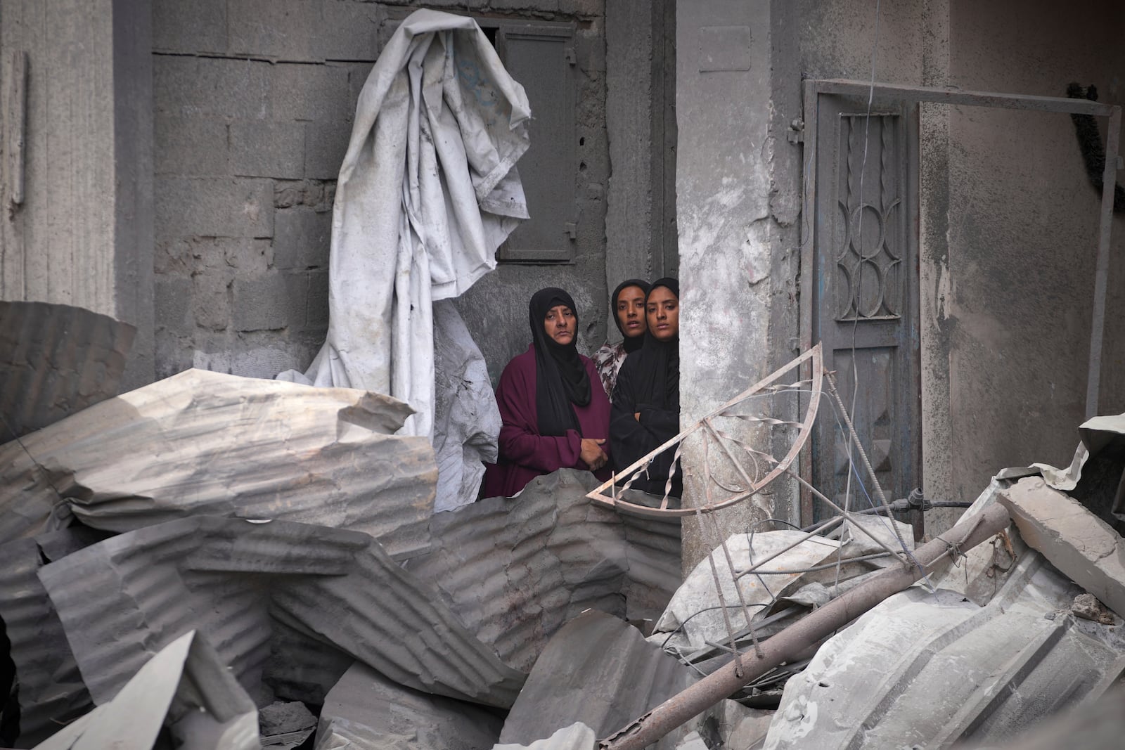 Palestinian women look as residents search the rubble of a house targeted by an Israeli army strike that killed killing at least five members of the Abu Sahloul family in Khan Younis, in the southern Gaza Strip, Thursday, May 1, 2025. (AP Photo/Abdel Kareem Hana)