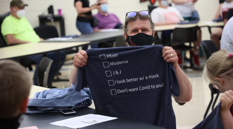 A man holds up a t-shirt he received after getting his COVID vaccination at Tecumseh High School. BILL LACKEY/STAFF