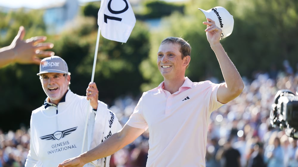 Jacob Bridgeman smiles next to caddie GW Cable after winning the Genesis Invitational golf tournament at Riviera Country Club, Sunday, Feb. 22, 2026, in the Pacific Palisades area of Los Angeles. (AP Photo/Caroline Brehman)