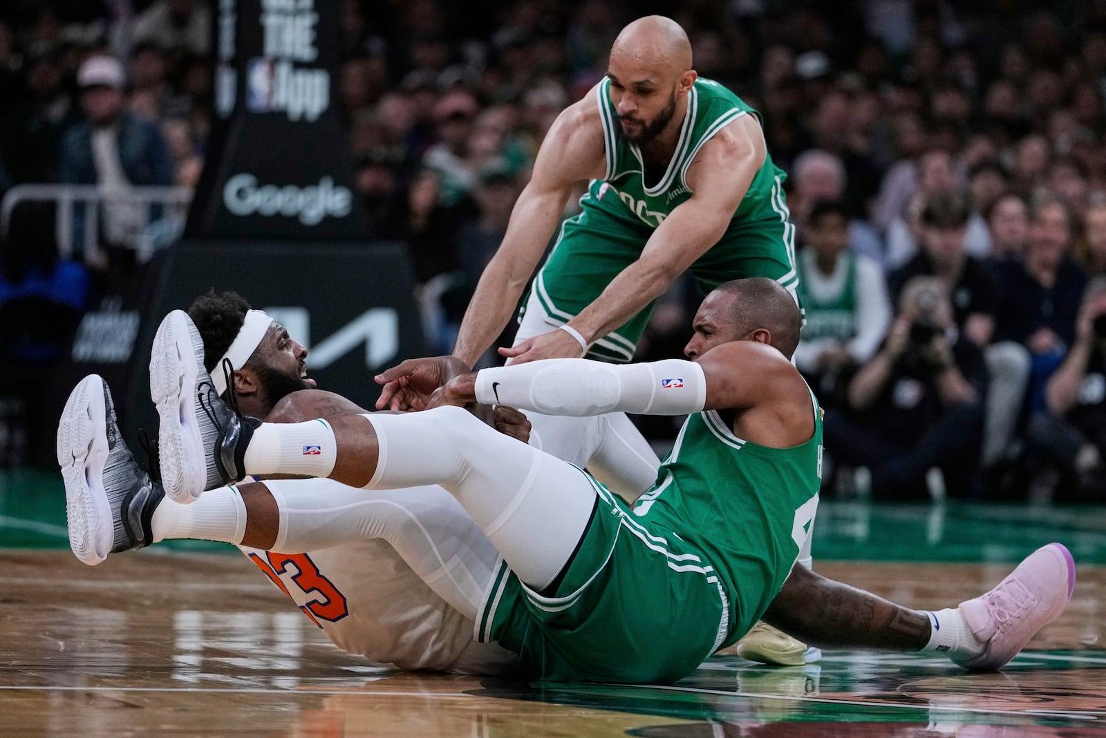 Boston Celtics center Al Horford, lower right, and guard Derrick White battle New York Knicks center Mitchell Robinson (23) for the ball during the first half of Game 2 of an NBA basketball second-round playoff series, Wednesday, May 7, 2025, in Boston. (AP Photo/Charles Krupa)
