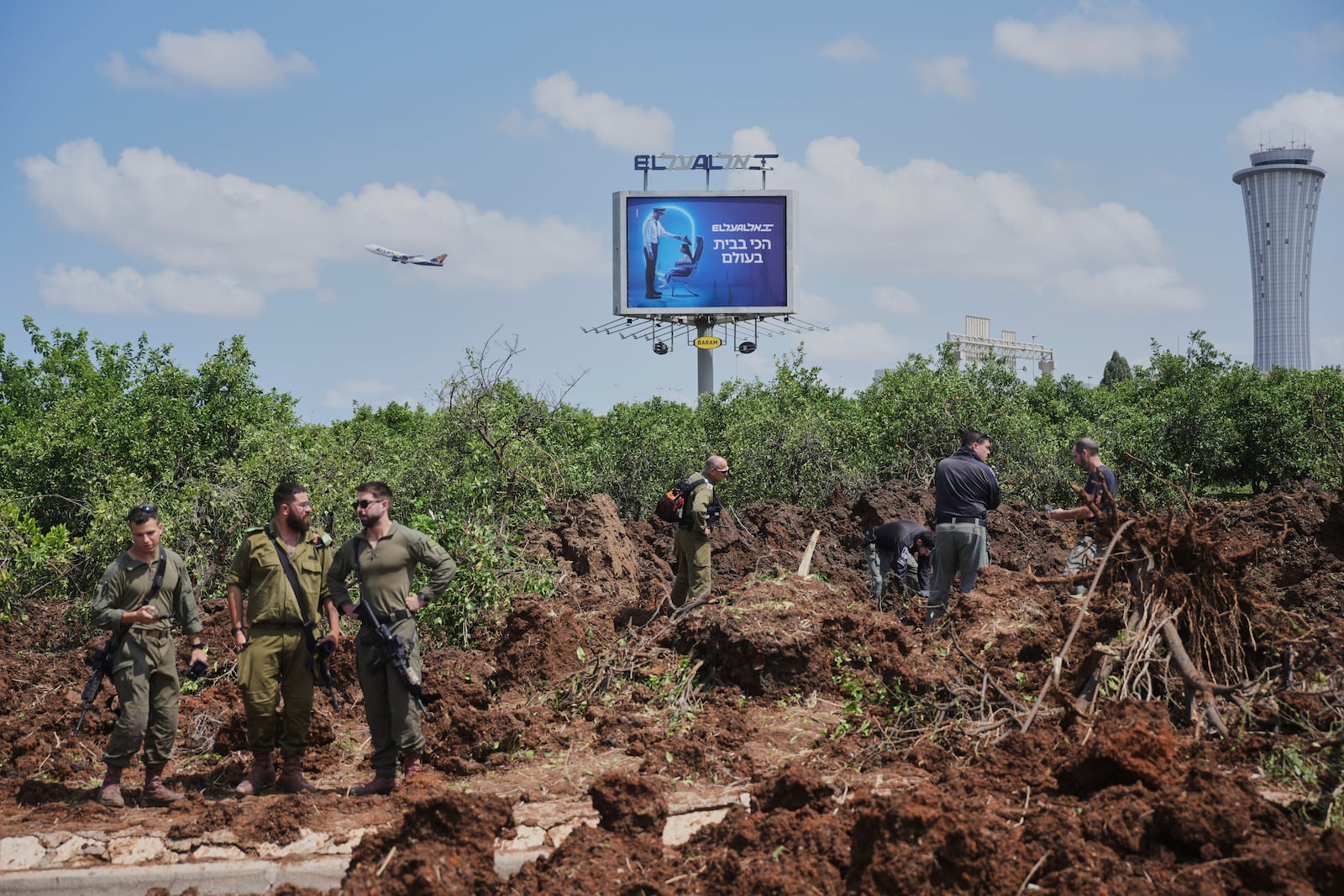 Israeli security forces inspect the site where the Israeli military said a projectile fired by Yemen's Houthi rebels landed in the area of Ben Gurion International Airport near Tel Aviv, Israel, on Sunday, May 4, 2025. (AP Photo/Ohad Zwigenberg)
