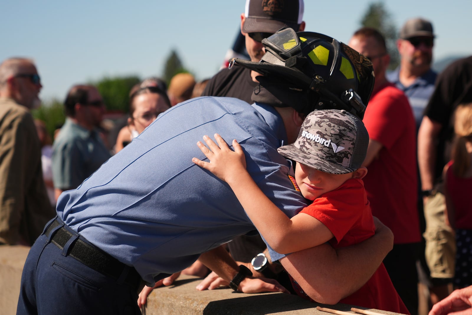 Coeur d'Alene firefighter Cody Moor greets friends, Troy Serticchio and Brayden, 8, as a crowd gathers to honor the firefighters who were killed Sunday, in Coeur d'Alene, Idaho, on Tuesday, July 1, 2025. (AP Photo/Lindsey Wasson)