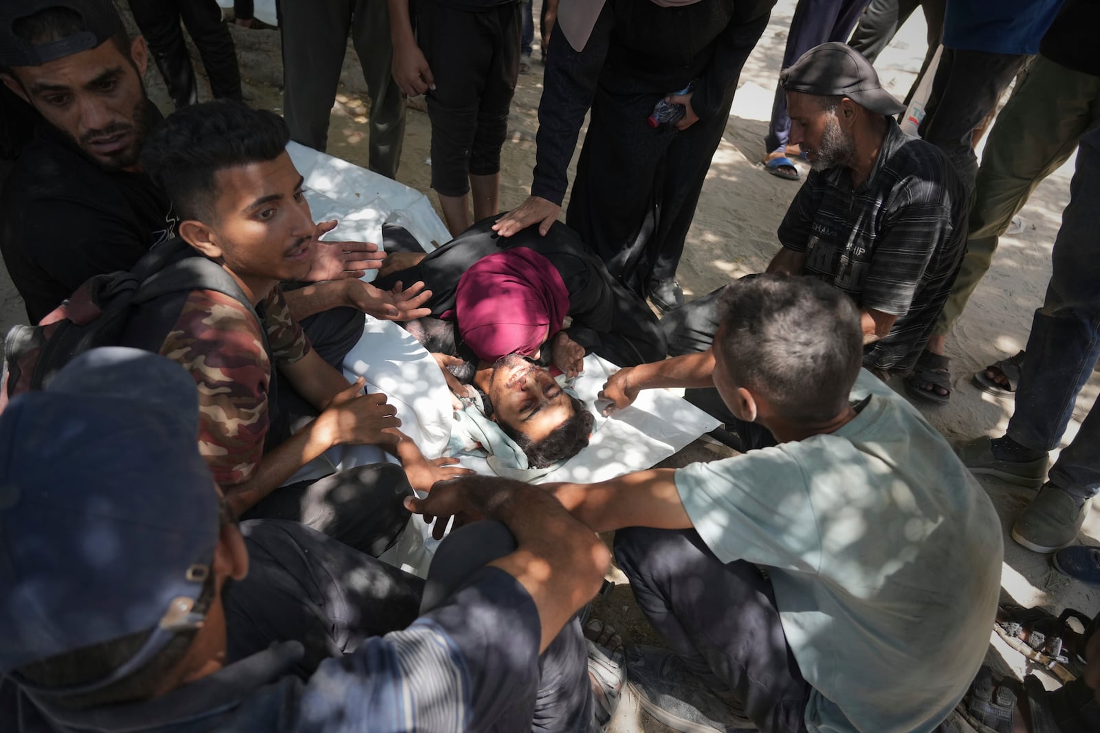 Palestinians mourn over the body of Ezzedine Qassem who was killed while attempting to access aid trucks entering northern Gaza through the Zikim crossing with Israel, at a clinic in Gaza City, Sunday, July 20, 2025. (AP Photo/Jehad Alshrafi)