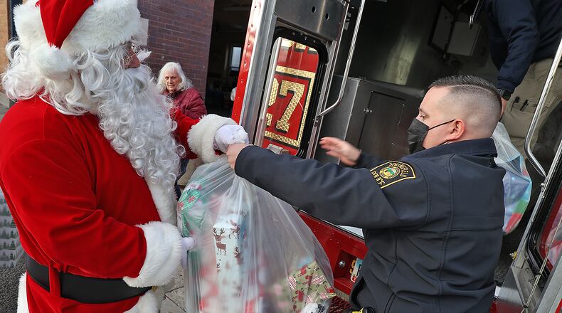 Santa hands off a bag full of gifts to Springfield Police Officer Zach Massie as they fill the Box 27 truck with presents to deliver to Springfield children in need this year. The gifts are all part of Operation Santa, a program in which some of the community's less-fortunate families receive Christmas gifts. The Springfield Police Department's Community Response Team works with local businesses and volunteers to shop, wrap and deliver the gifts for the holiday. BILL LACKEY/STAFF
