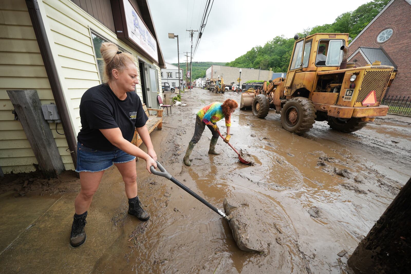 From left, Ashley Rishel from the Allegany County 911 and Lesley Moran help clean up Main Street after flooding on Wednesday, May 14, 2025 in Westernport, Md. (AP Photo/Gene J. Puskar)