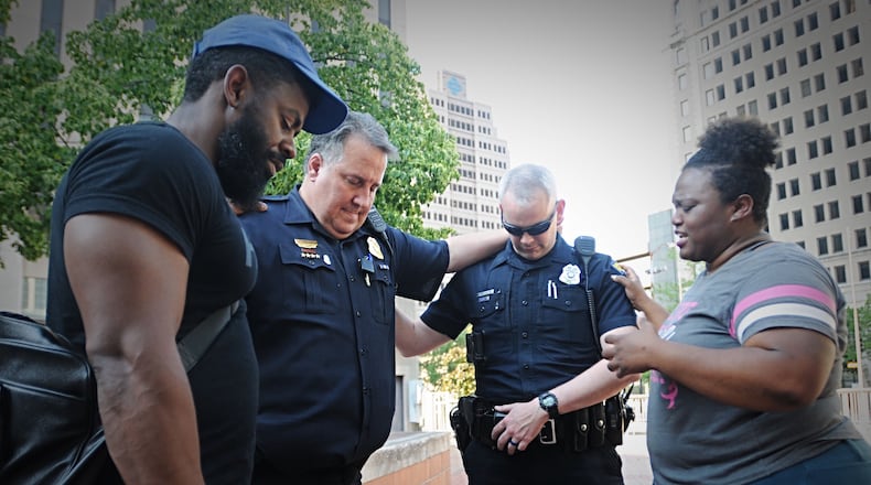 Officer Will Davis, Sergeant Chad Knight, Natasha Hunter and a man who wished not to be identified, pray together at Courthouse Square after a foot washing ceremony. Marshall Gorby/Staff photo