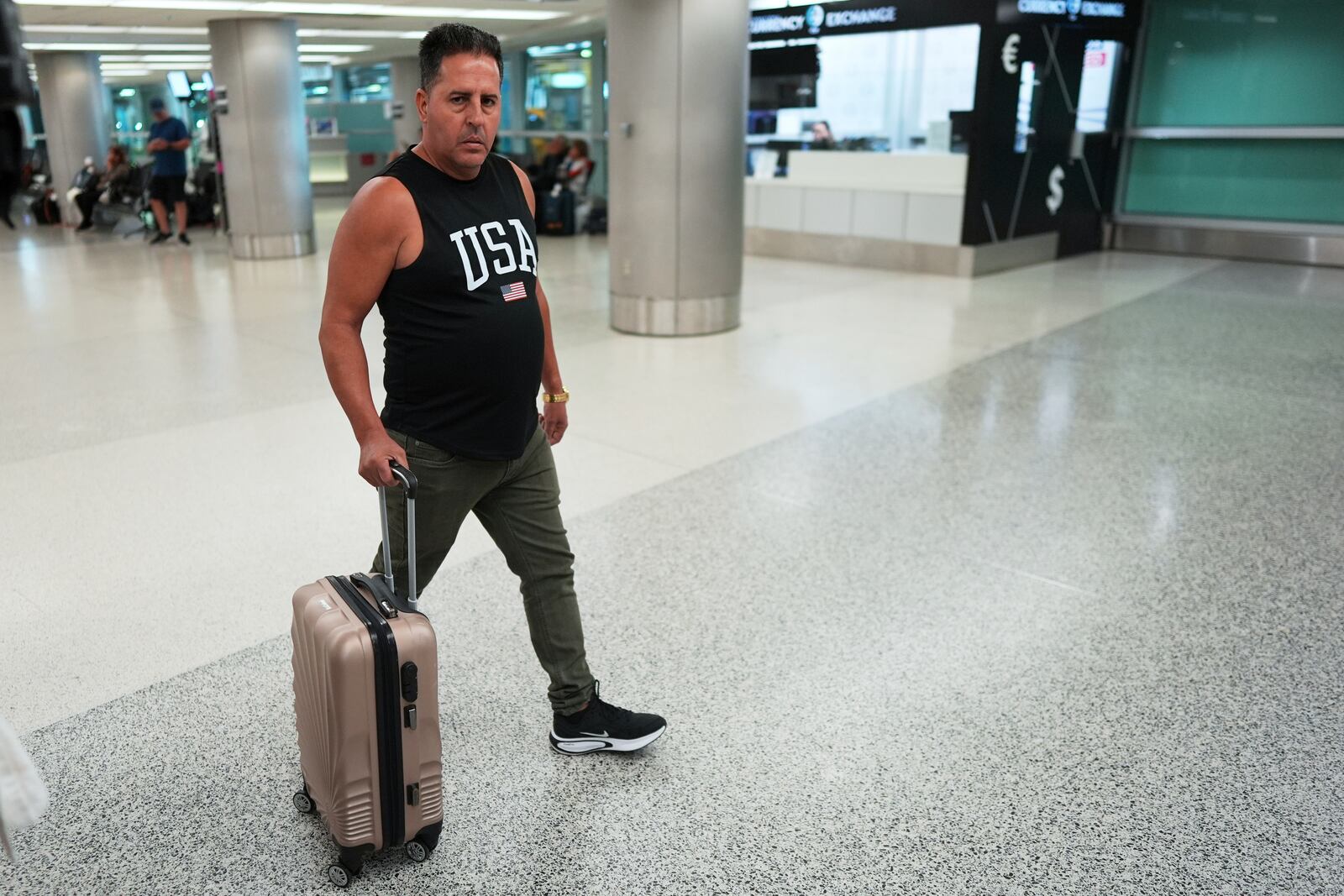 A man arriving from Cuba wears a USA tee-shirt, as he walks out of international arrivals at Miami International Airport, Monday, June 9, 2025, in Miami. (AP Photo/Rebecca Blackwell)