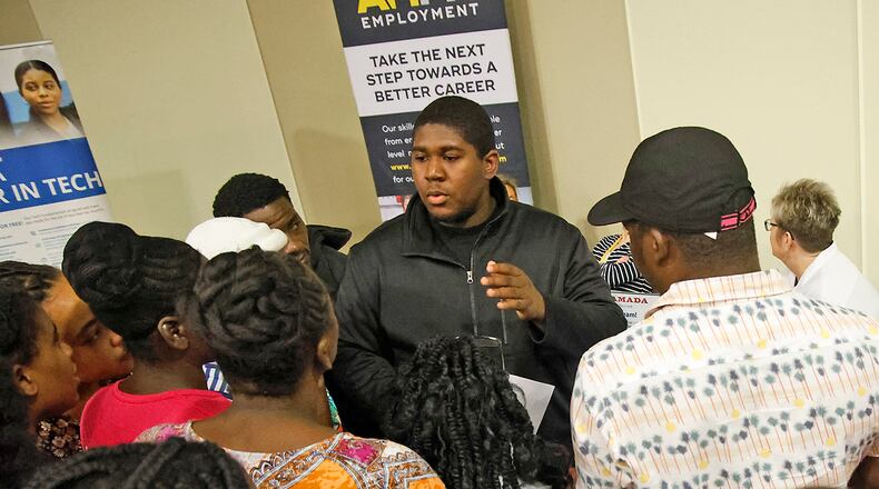 Members of Springfield's Haitian community gather around Bradley Jean, center, as he translates for them at the 14th Annual Clark County Job Fair Wednesday, April 17, 2024. The job fair featured 60 employers looking for skilled and unskilled workers.  BILL LACKEY/STAFF