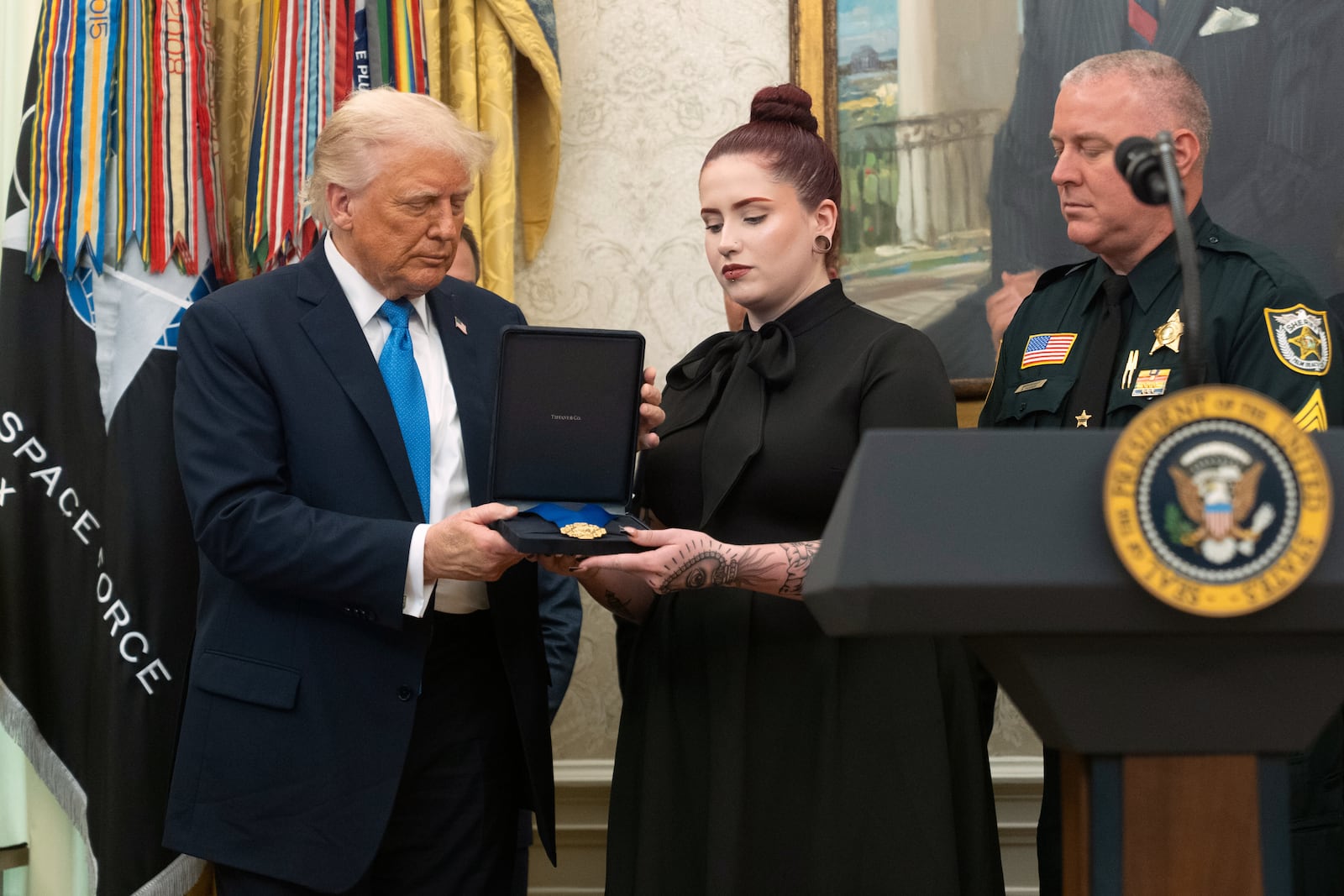 President Donald Trump presents a Medal of Sacrifice to Alexandria Diaz, center, honoring her late father Deputy Sheriff Ignacio "Dan" Diaz, during a ceremony in the Oval Office at the White House, Monday, May 19, 2025, in Washington. (AP Photo/Manuel Balce Ceneta)