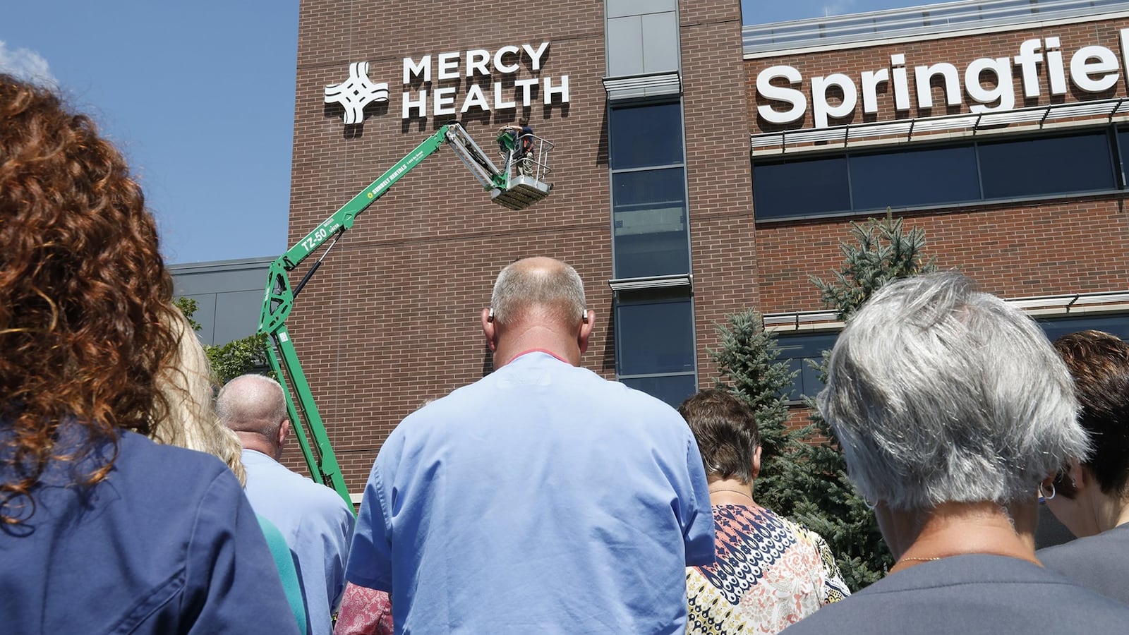 Pictured in August 2017, employees at Springfield Regional Medical Center bow their heads in prayer as a new Mercy Health sign is unveiled. The Collaboratory, the Mercy Health Foundation, the Turner Foundation, the nonprofit Undue Medical Debt and others are currently working on a campaign to eliminate $9.1 million in medical debt in Clark County by raising $51,000 to purchase that debt and forgive it. Ben Merick, vice president of market operations for the Springfield market, said Mercy Health's participation in these efforts stem from the organization's religious roots. BILL LACKEY/STAFF FILE