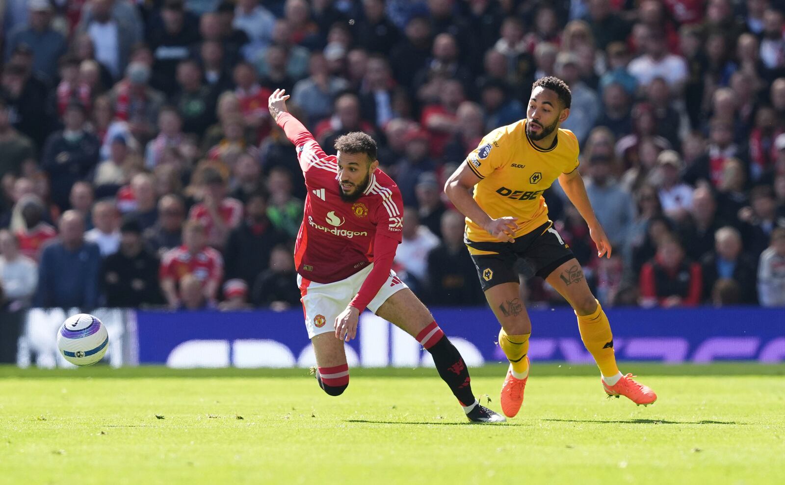 Manchester United's Noussair Mazraoui, left and Wolverhampton Wanderers' Matheus Cunha vie for the ball, during the English Premier League soccer match between Manchester United and Wolverhampton Wanderers, at Old Trafford, Manchester, England, Sunday, April 20, 2025. (Martin Rickett/PA via AP)