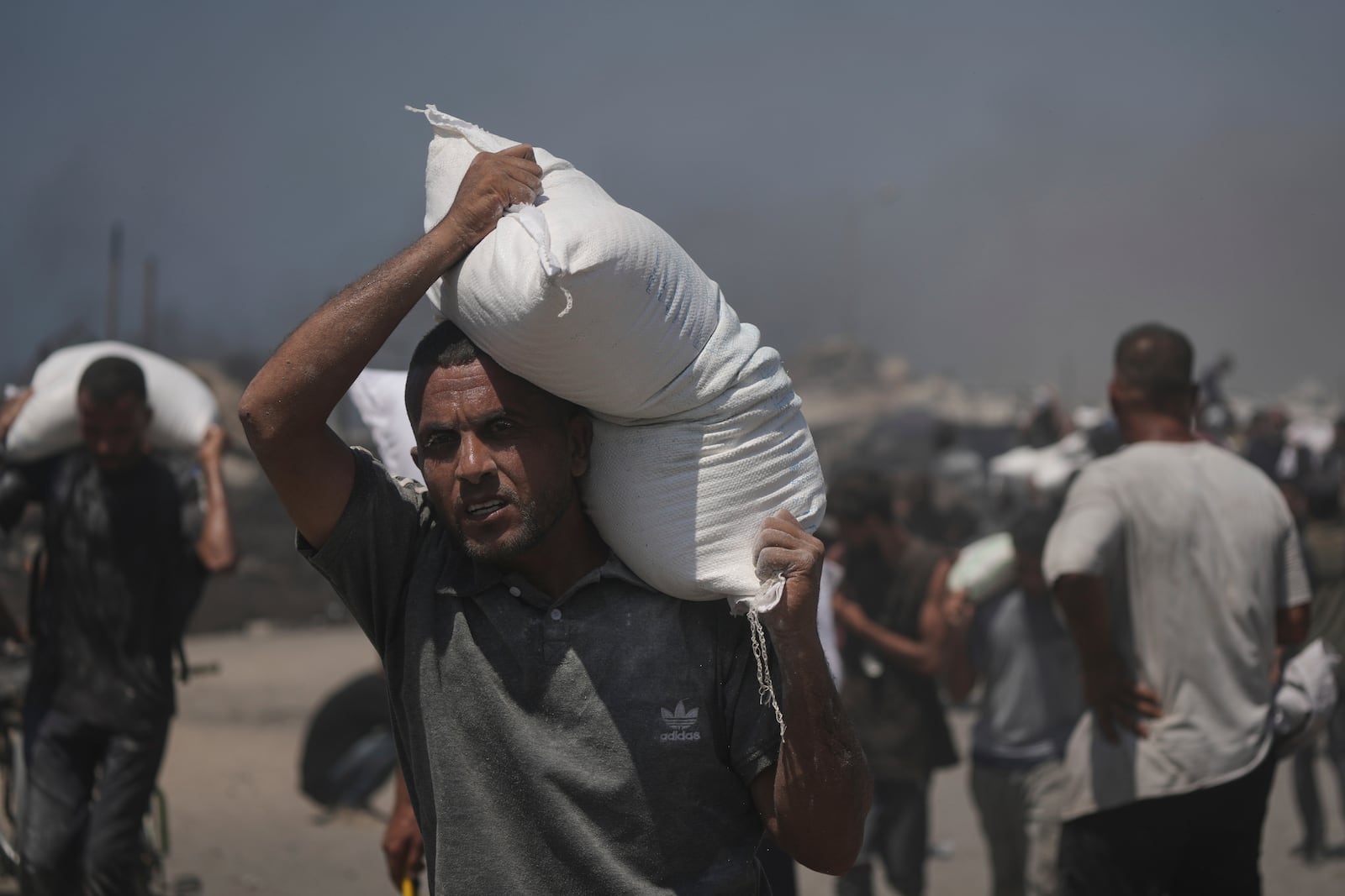 Palestinians carry sacks of flour unloaded from a humanitarian aid convoy that reached Gaza City from the northern Gaza Strip, Sunday, July 27, 2025. (AP Photo/Jehad Alshrafi)