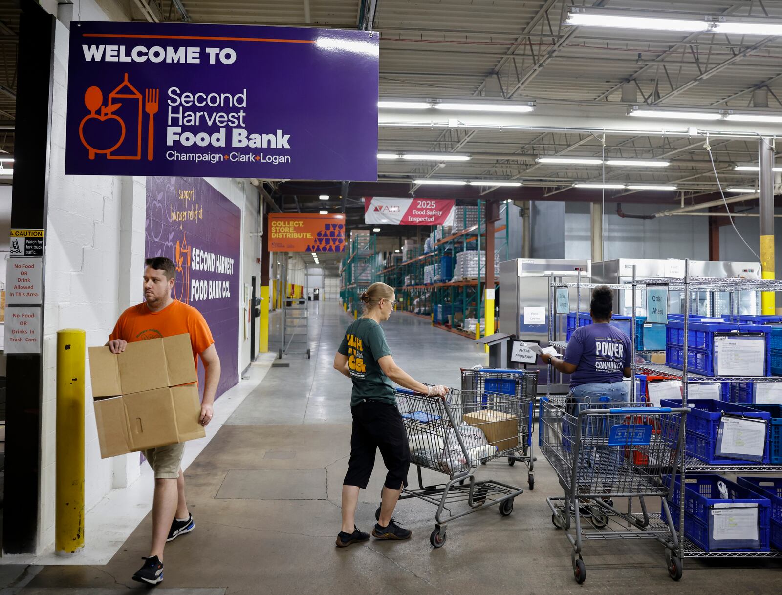 Volunteers Kurt Heltman, left, Carol Conrad, center, and distribution specialist Shauna Riggins work in the warehouse of Second Harvest Food Bank on Wednesday, July 9, 2025, in Springfield. JOSEPH COOKE/STAFF