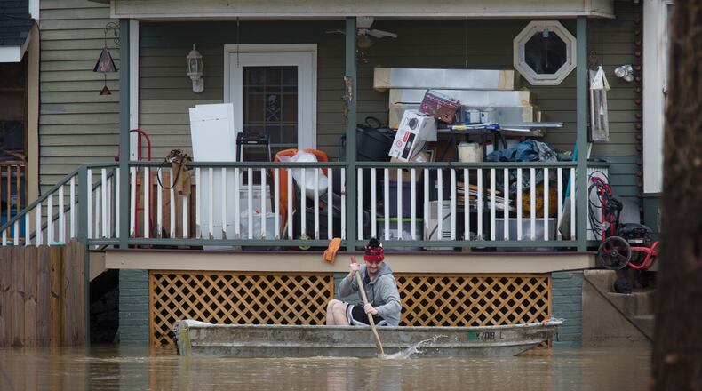 A man paddles his boat alongside a home in the East End along the Ohio River, Saturday, Feb. 24, 2018, in Cincinnati. Forecasters expected the Ohio River could reach levels not seen since the region's deadly 1997 floods. (Liz Dufour/The Cincinnati Enquirer via AP)