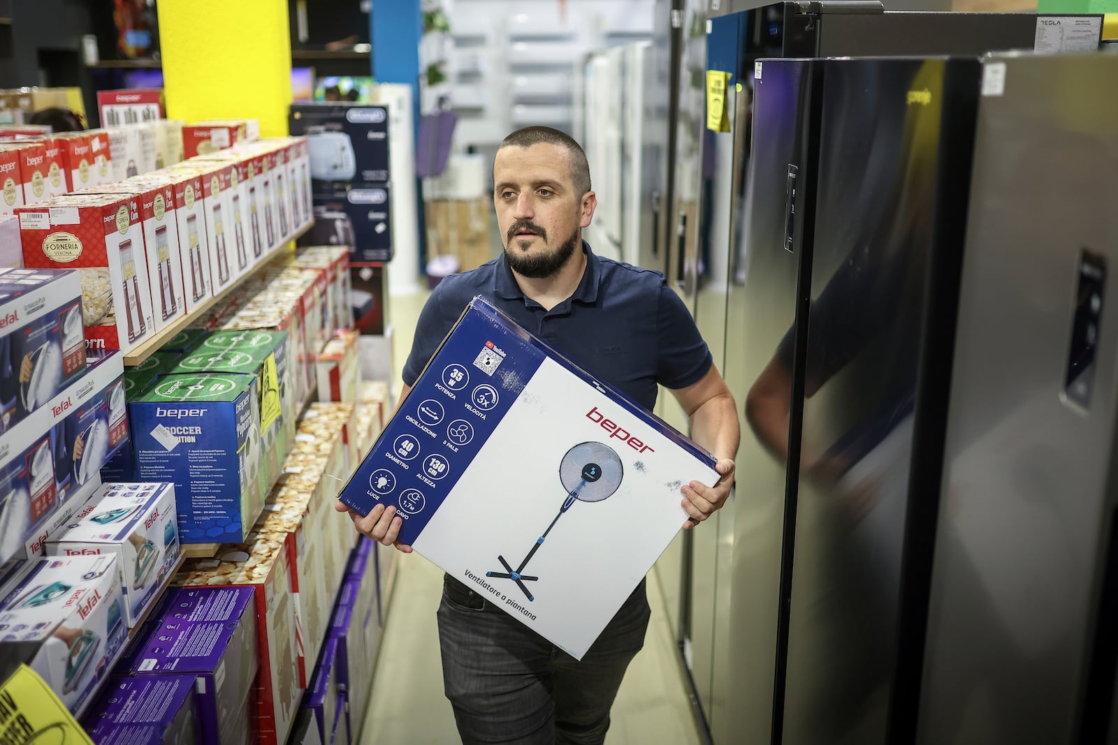Tarik Fatic, one of the owners of "Only fools and horses ltd." home appliance store, brings a fan to a customer in Hadzici, suburb of Sarajevo, Bosnia, Wednesday, June 4, 2025. (AP Photo/Armin Durgut)