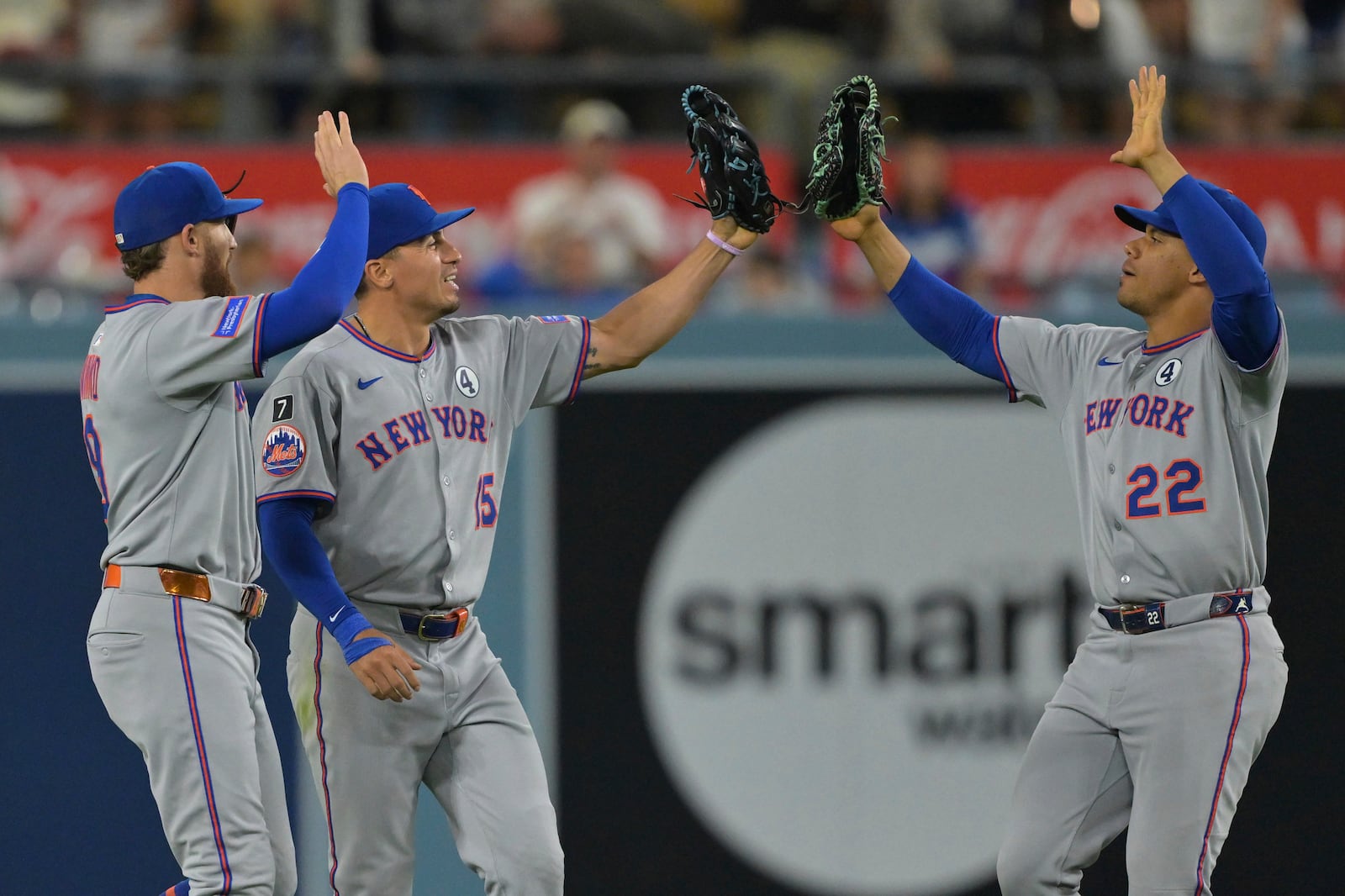 New York Mets left fielder Brandon Nimmo, left, Mets center fielder Tyrone Taylor and Mets right fielder Juan Soto (22) high five after the final out in the tenth inning of a baseball game against the Los Angeles Dodgers, Monday, June 2, 2025, in Los Angeles. (AP Photo/Jayne Kamin-Oncea)