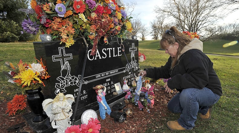 Barbara Castle straightens some of the items surrounding her mother’s grave at Ferncliff Cemetery on Wednesday evening. Castle is upset because someone has been stealing the solar lights that she’s placed around the grave marker because her mother was afraid of the dark. Bill Lackey/Staff