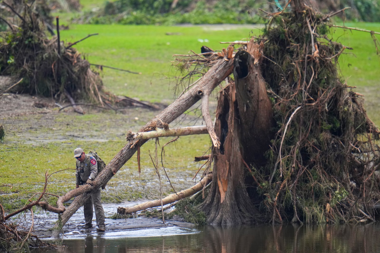 A Texas Department of Public Safety official inspects tree debris at Camp Mystic along the Guadalupe River after a flash flood swept through the area Sunday, July 6, 2025, in Hunt, Texas. (AP Photo/Julio Cortez)