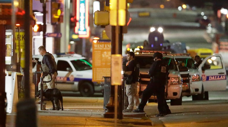 Law enforcement sweep the area after a shooting in downtown Dallas, Friday, July 8, 2016. At least two snipers opened fire on police officers during protests in Dallas on Thursday night; some of the officers were killed, police said. (AP Photo/LM Otero)