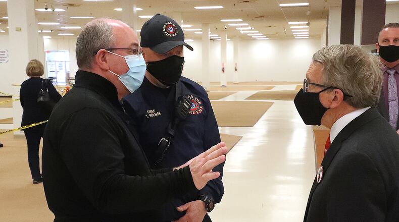 German Township Fire Chief Tim Holman and Clark County Health Commissioner Charles Patterson talk to Governor Mike DeWine during the governor's recent stop at the COVID vaccine distribution center in Clark County. BILL LACKEY/STAFF