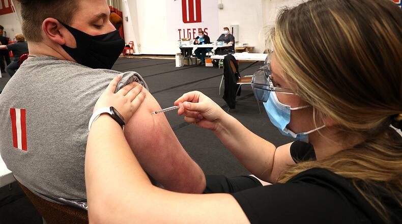 Logan Lange, a junior at Wittenberg University, gets his COVID vaccine from Wittenberg student nurse Camille Odle on April 9 in the Pam Evans Smith Arena on the Wittenberg campus. On Friday, Clark County's health commissioner said COVID-19 cases are falling in the county because more people are getting vaccinated. BILL LACKEY/STAFF