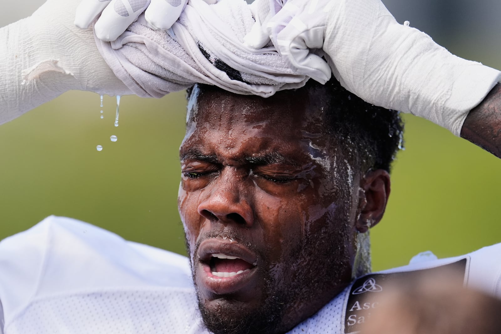 Tennessee Titans linebacker Arden Key uses a wet towel to cool off after practice at the team's NFL football training camp, Tuesday, July 29, 2025, in Nashville, Tenn. (AP Photo/George Walker IV)