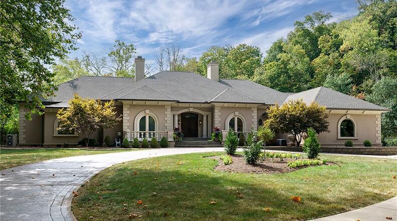 A circular brick paver and concrete driveway winds through the wooded property to the front of the home.