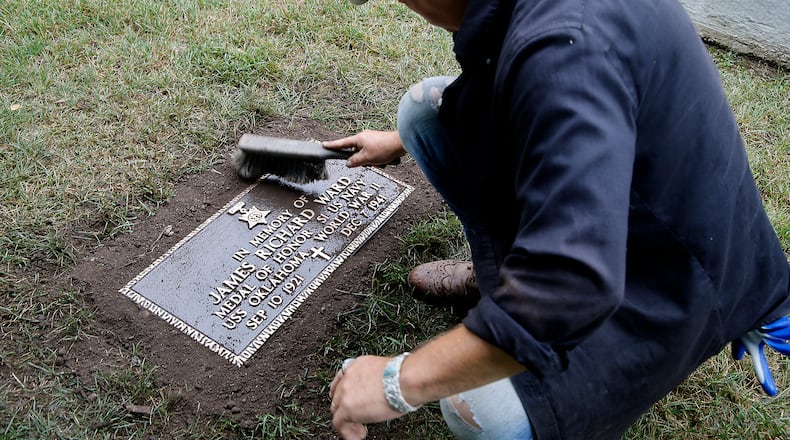 Rob Kelly, a member of the Ferncliff Cemetery grounds crew, brushes off the new grave marker for Medal of Honor winner and Clark County native James Richard Ward after placing it in the World War II veterans section at Ferncliff Wednesday, July 10, 2024. The remains of Ward, who was killed on the USS Oklahoma at Pearl Harbor, were recently recovered and identified. His family asked for him to be buried at Arlington Cemetery in Washington D.C. and according to military rules, a veteran can only have one military grave marker and the marker that was placed at Ferncliff was removed. The cemetery recently had another marker made and today it was placed where the old marker was located. BILL LACKEY/STAFF