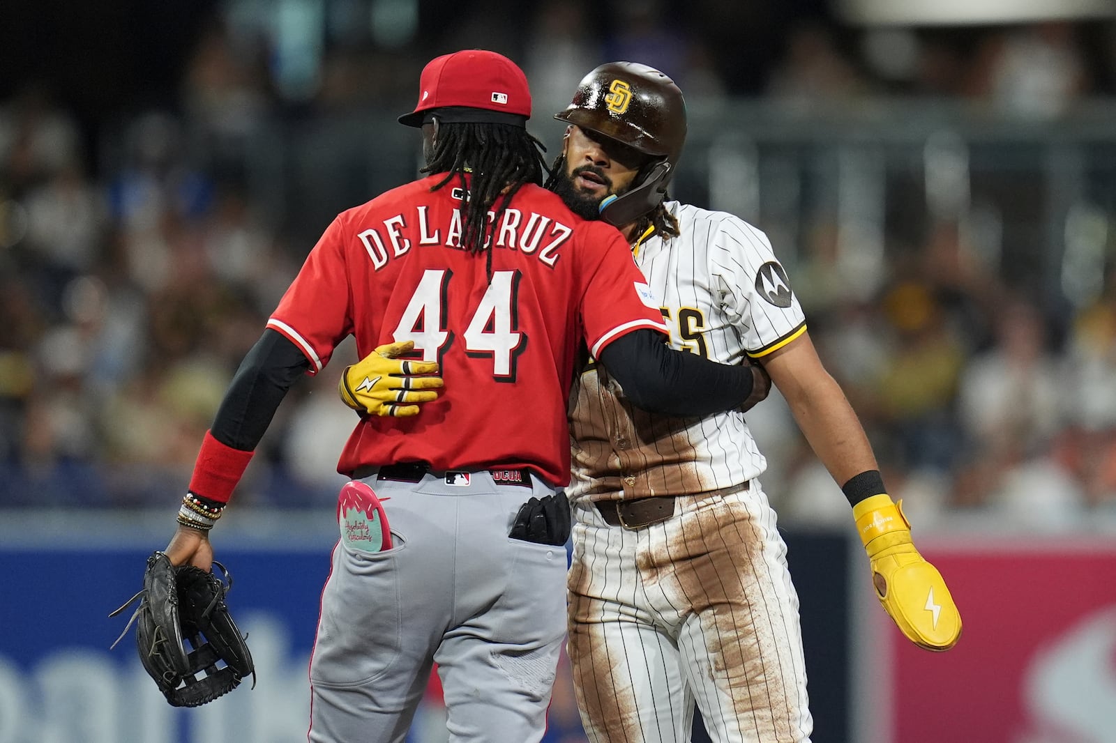 Cincinnati Reds shortstop Elly De La Cruz (44) embraces San Diego Padres' Fernando Tatis Jr. after Tatis Jr stole second base during the sixth inning of a baseball game Monday, Sept. 8, 2025, in San Diego. (AP Photo/Gregory Bull)