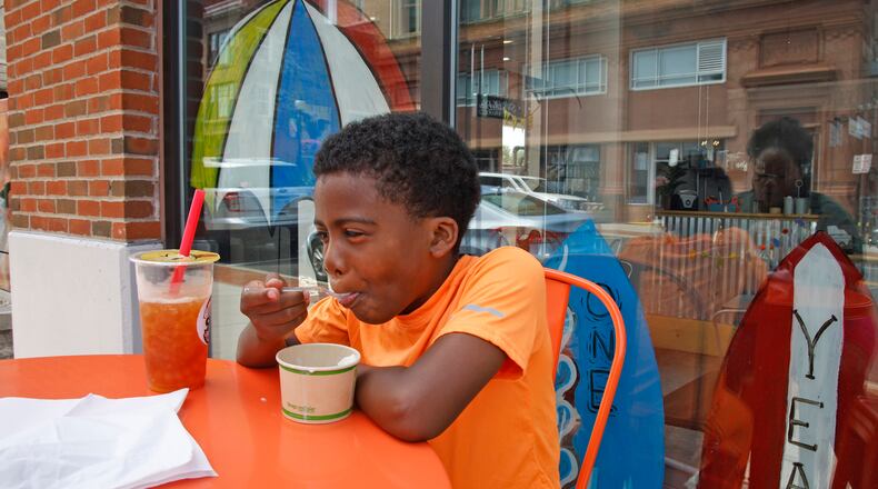 Jeremiah Leslie, 10, finds some relief from the heat as he enjoys some ice cream and a boba tea with his mother outside Champion City Pops Thursday, June 20, 2024. BILL LACKEY/STAFF