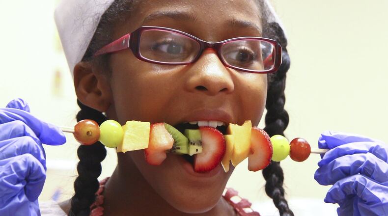 Madison Smith devours a self-made fruit kebab while taking a cooking class for teens called iCook during the “You Are What You Eat” program at St. John Missionary Baptist Church in June of 2013. Barbara J. Perenic/Staff