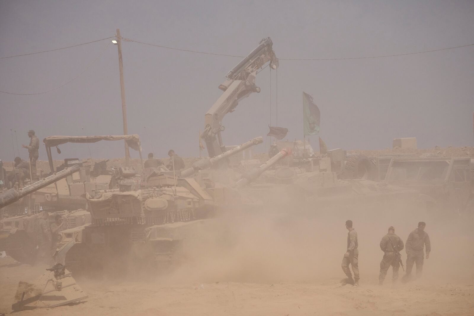 Israeli soldiers work on their tanks in a staging area on the border with Gaza Strip, in southern Israel, Tuesday, July 29, 2025. (AP Photo/Ariel Schalit)