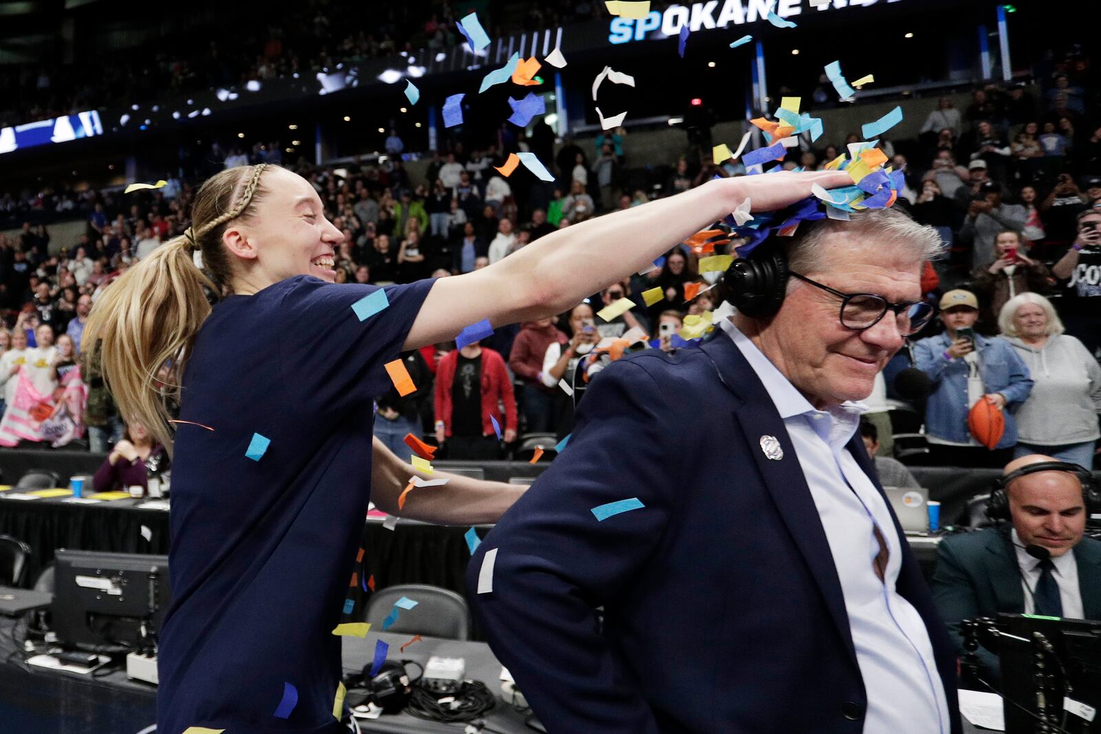 UConn guard Paige Bueckers, left, places confetti onto head coach Geno Auriemma, front right, after the team's win over Southern California in the Elite Eight of the NCAA college basketball tournament, Monday, March 31, 2025, in Spokane, Wash. (AP Photo/Young Kwak)