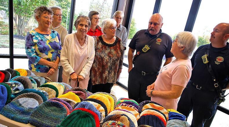 Lt. Felix Shanahan with the Springfield Fire Rescue Division, center, talks about the need the department sees for the warm hats the ladies from the Springfield Masonic Community made for them to pass out. The ladies knitted and crocheted more than 120 hats in three weeks for the people of Springfield in need this winter. BILL LACKEY/STAFF