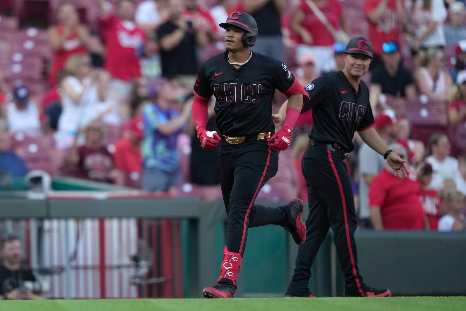Cincinnati Reds' Noelvi Marte rounds third base as third base coach J.R. House, right, looks on after hitting a solo home run during the third inning of a baseball game against the Colorado Rockies in Cincinnati, Friday, July 11, 2025. (AP Photo/Carolyn Kaster)