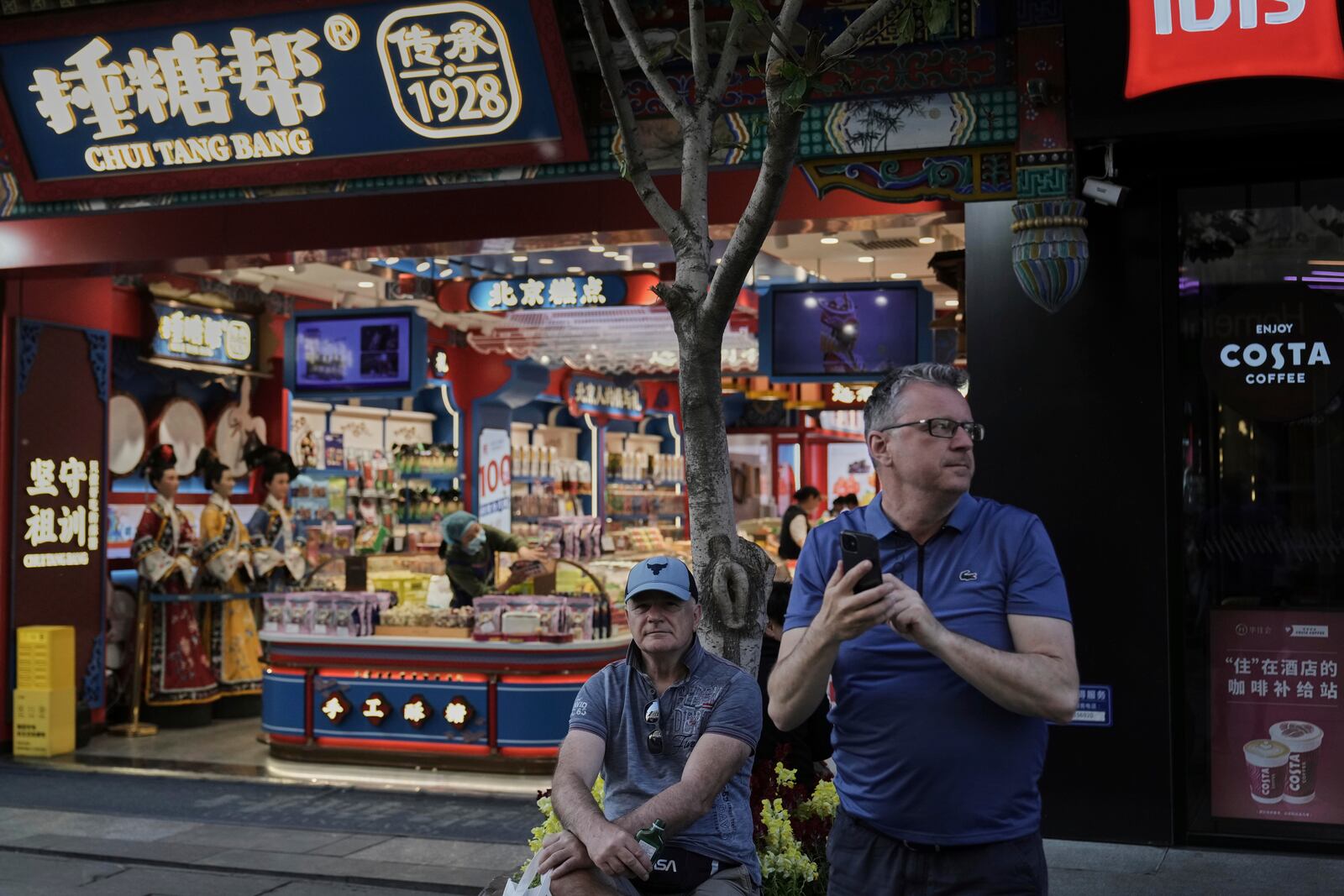 Tourists take a rest outside a souvenir store at Qianmen pedestrian shopping street in Beijing, Sunday, April 27, 2025. (AP Photo/Andy Wong)